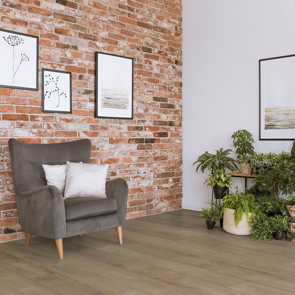 A living room with a brick wall , a chair , and potted plants.
