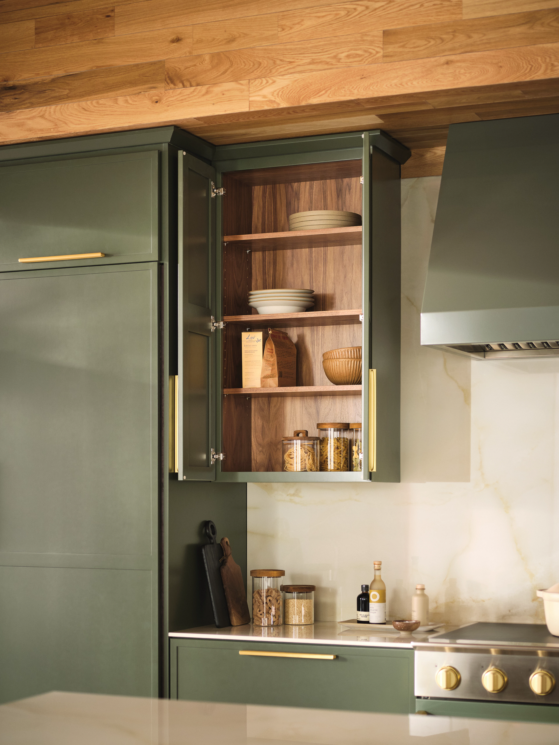 A kitchen with green cabinets and wooden shelves.