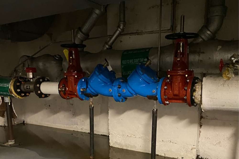 Plumbing pipes with red and blue valves in a basement.
