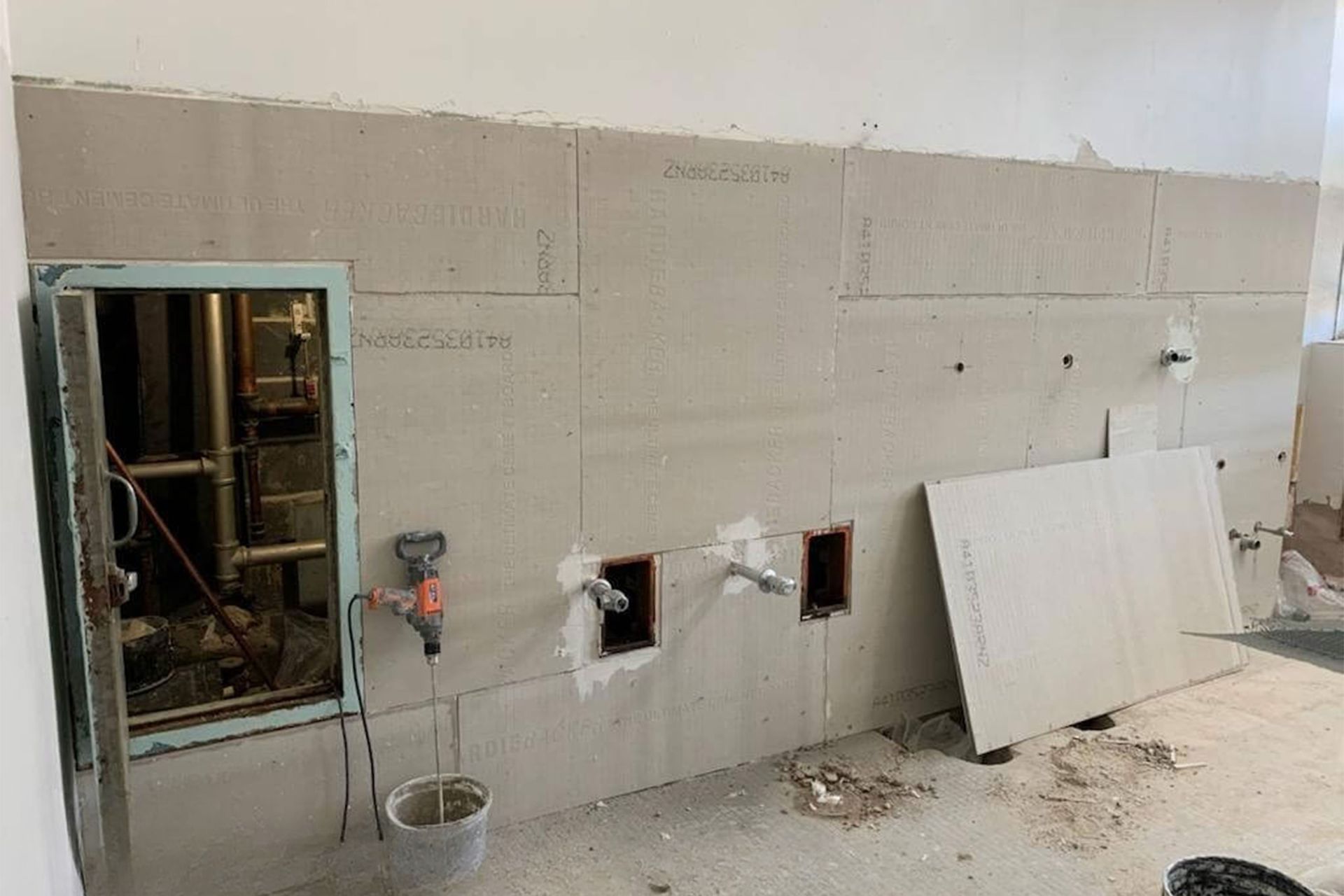 Construction in progress; drywall installed on a wall with plumbing fixtures.