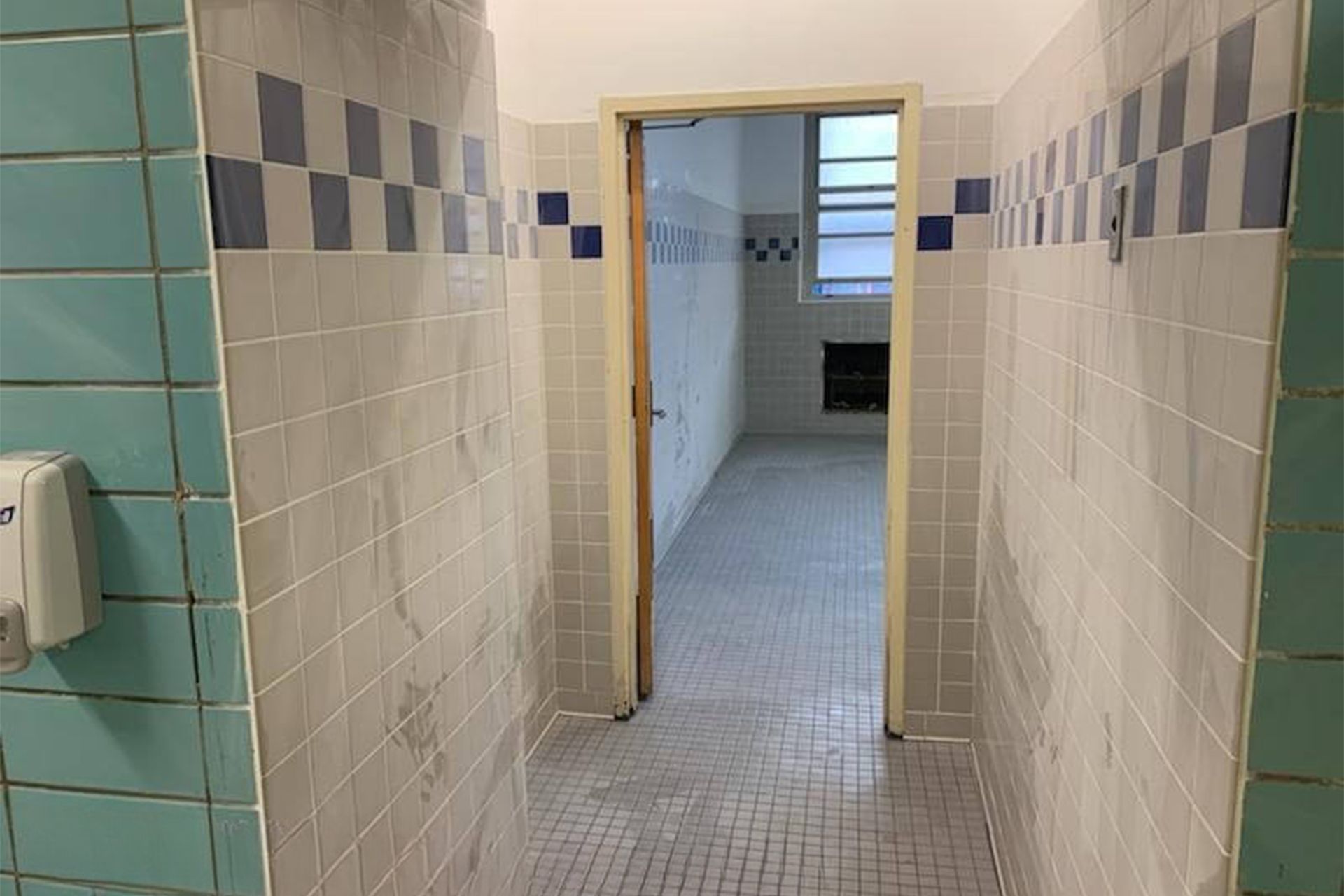 Narrow tiled hallway with an open doorway to another room.
