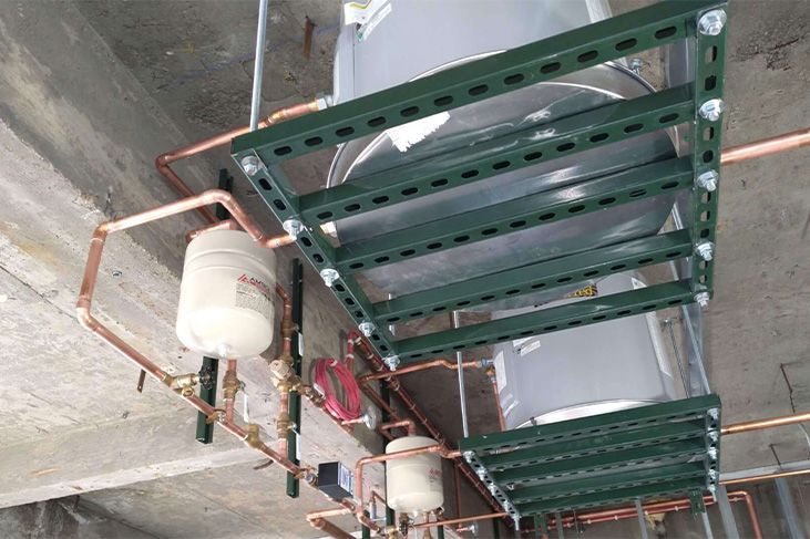 Water heater system, green metal shelving, copper pipes against a concrete ceiling.