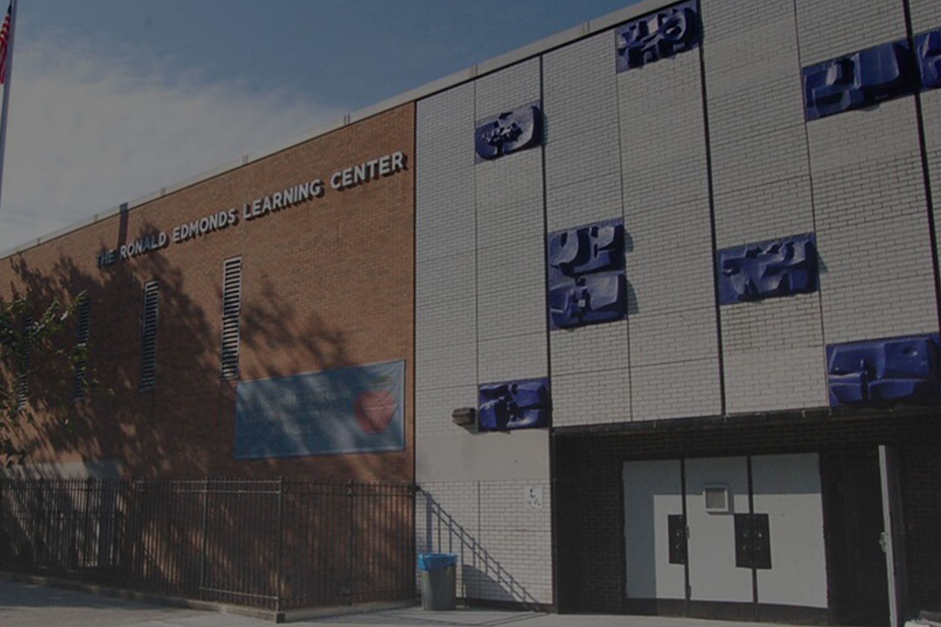 Building: Maria Sanchez Learning Center, exterior view. Red brick and white wall with blue art pieces.