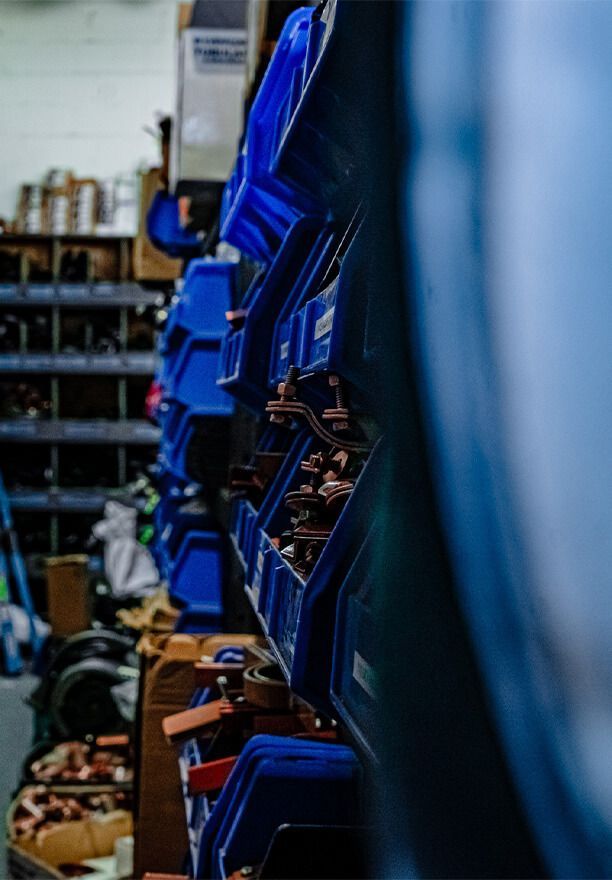Blue bins filled with parts on a shelf in a warehouse.