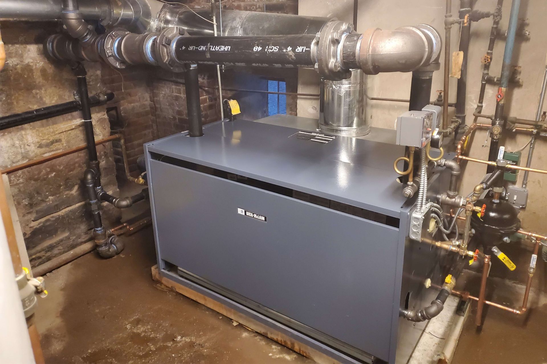 Blue boiler in a utility room with pipes and metal fittings.