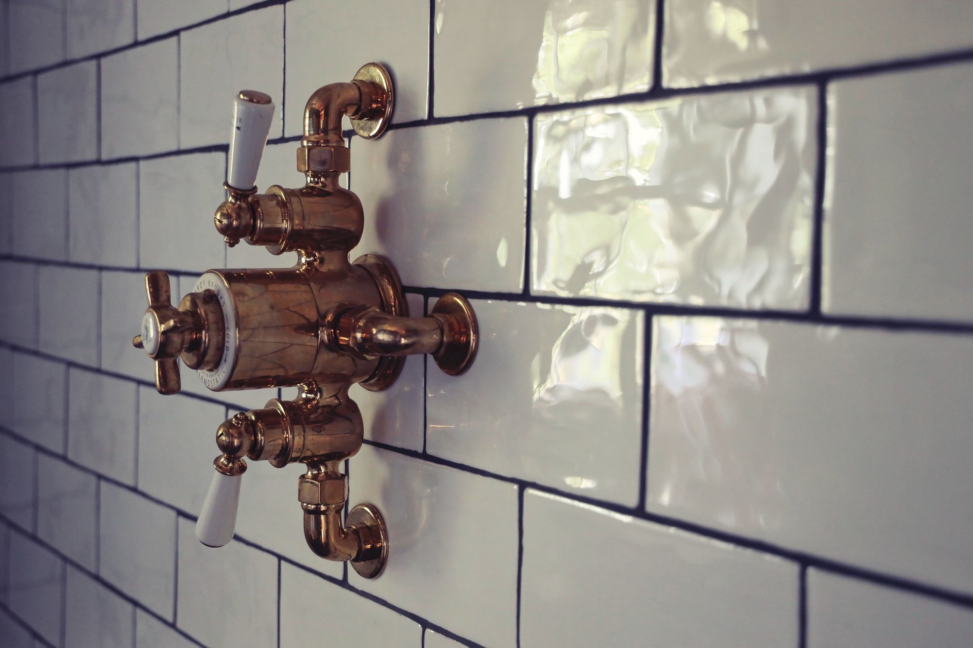 Gold shower fixtures on white subway tile wall.