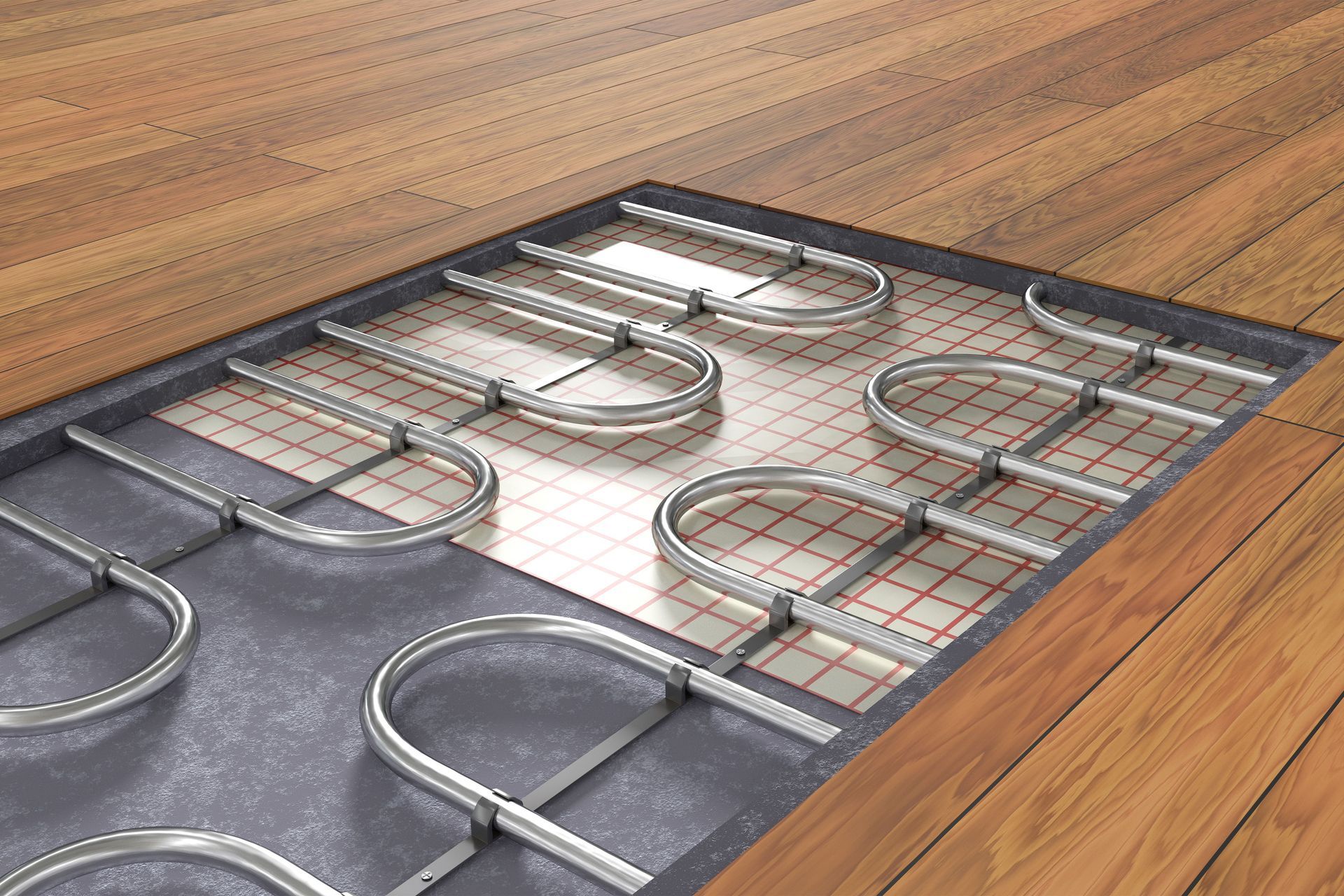 Underfloor heating system installation with metal pipes laid on a grid, beneath wooden flooring.