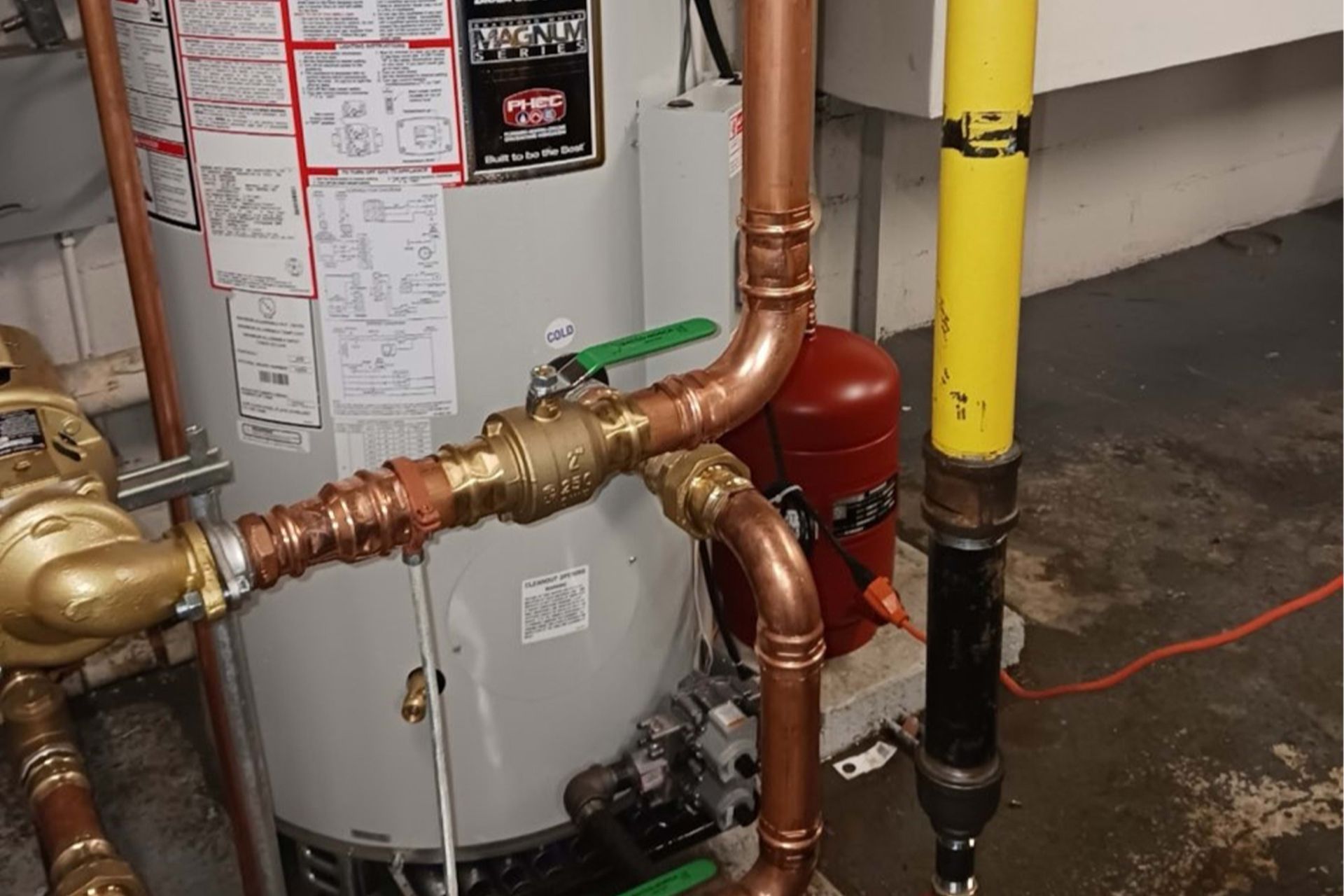 Copper plumbing pipes connected to a water heater and other fixtures in a utility room.