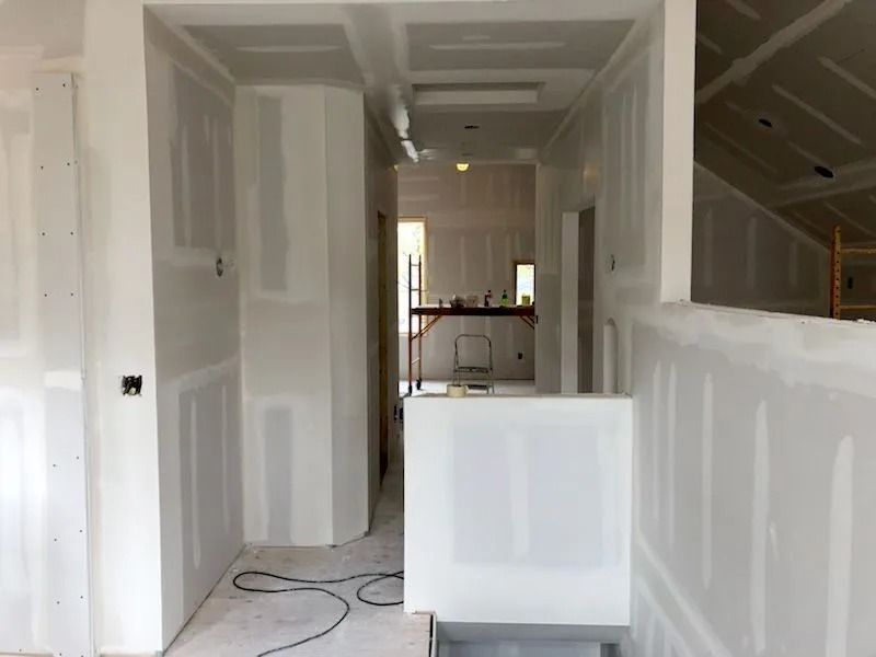 Interior hallway under construction with drywall installed on walls and ceiling.