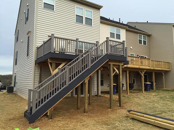 Raised wooden staircase leading to a tan house on stilts with a deck and railing
