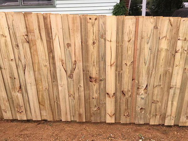 Wooden privacy fence along a yard, with house siding visible above it.