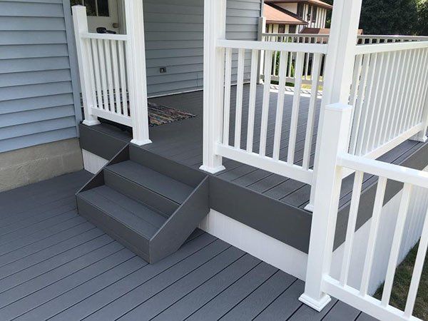 Porch with gray steps, white railings, and a small ramp leading to a house entrance
