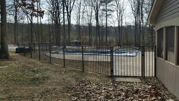 Backyard view with a fenced-in pool beside a house and leafless trees in the background