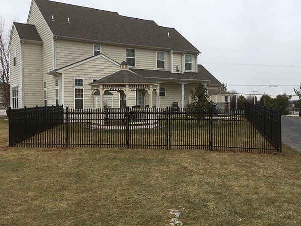 Suburban house with fenced backyard and a covered patio on a cloudy day