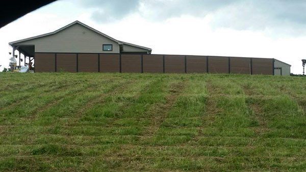 Brown building behind a fence on a grassy hill under an overcast sky