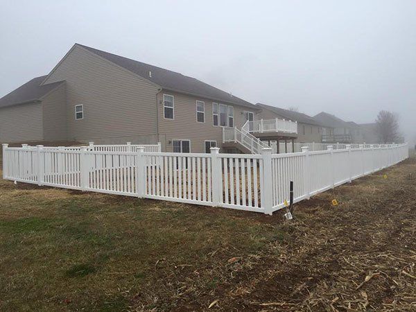 White fenced backyard beside a beige house in foggy weather