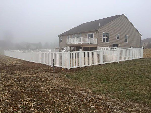 House with white fence on a foggy rural lot
