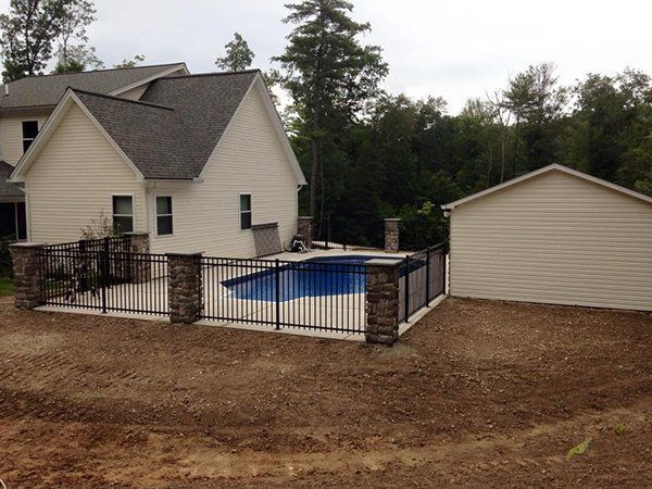 House with fenced backyard pool and beige shed on a wooded lot