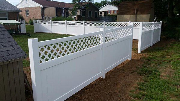 White vinyl fence with lattice top bordering a residential yard and walkway