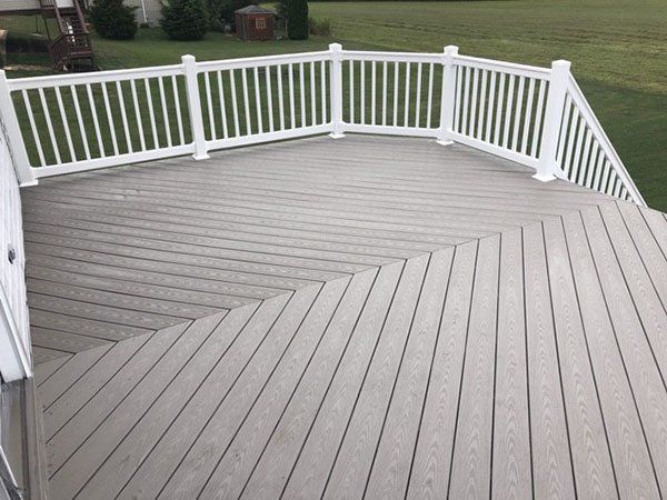 Gray wooden deck with white railings and stairs leading to a grassy yard