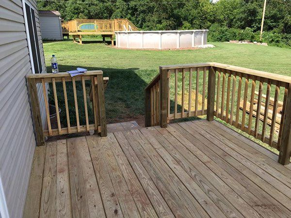 Wooden back deck overlooking a backyard with a small above-ground pool and a shed in the distance