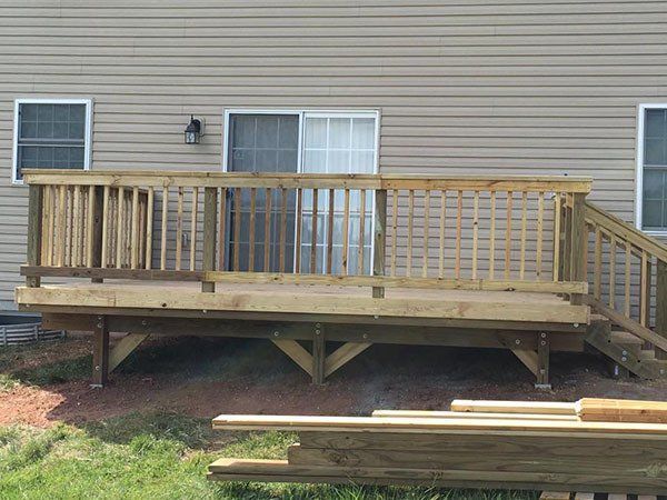 Wooden deck with railing and stairs attached to a beige house exterior