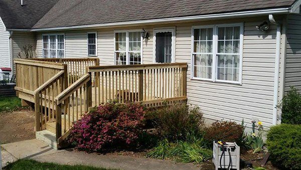 Single-story house with a wooden accessibility ramp and railing beside the front entry.