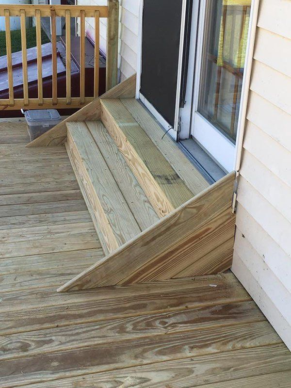 Weathered wooden accessibility ramp leading to a sliding glass door on a porch