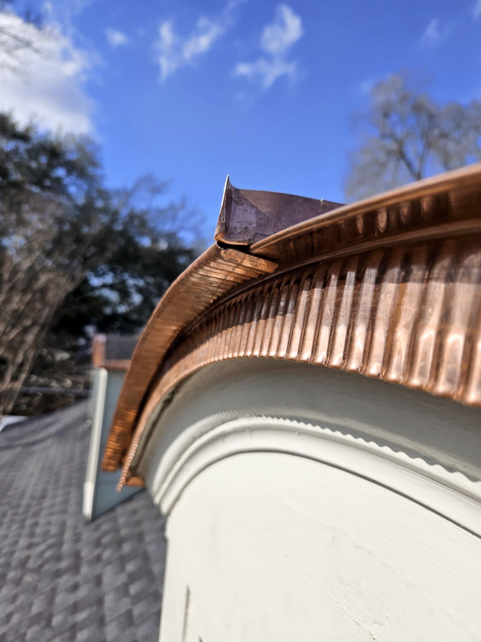 Copper guttering on a white building, with a clear blue sky backdrop.