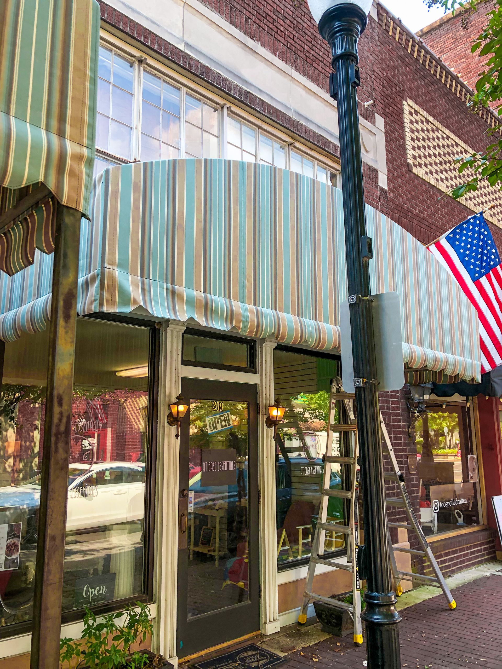 Storefront with striped awning and American flag.