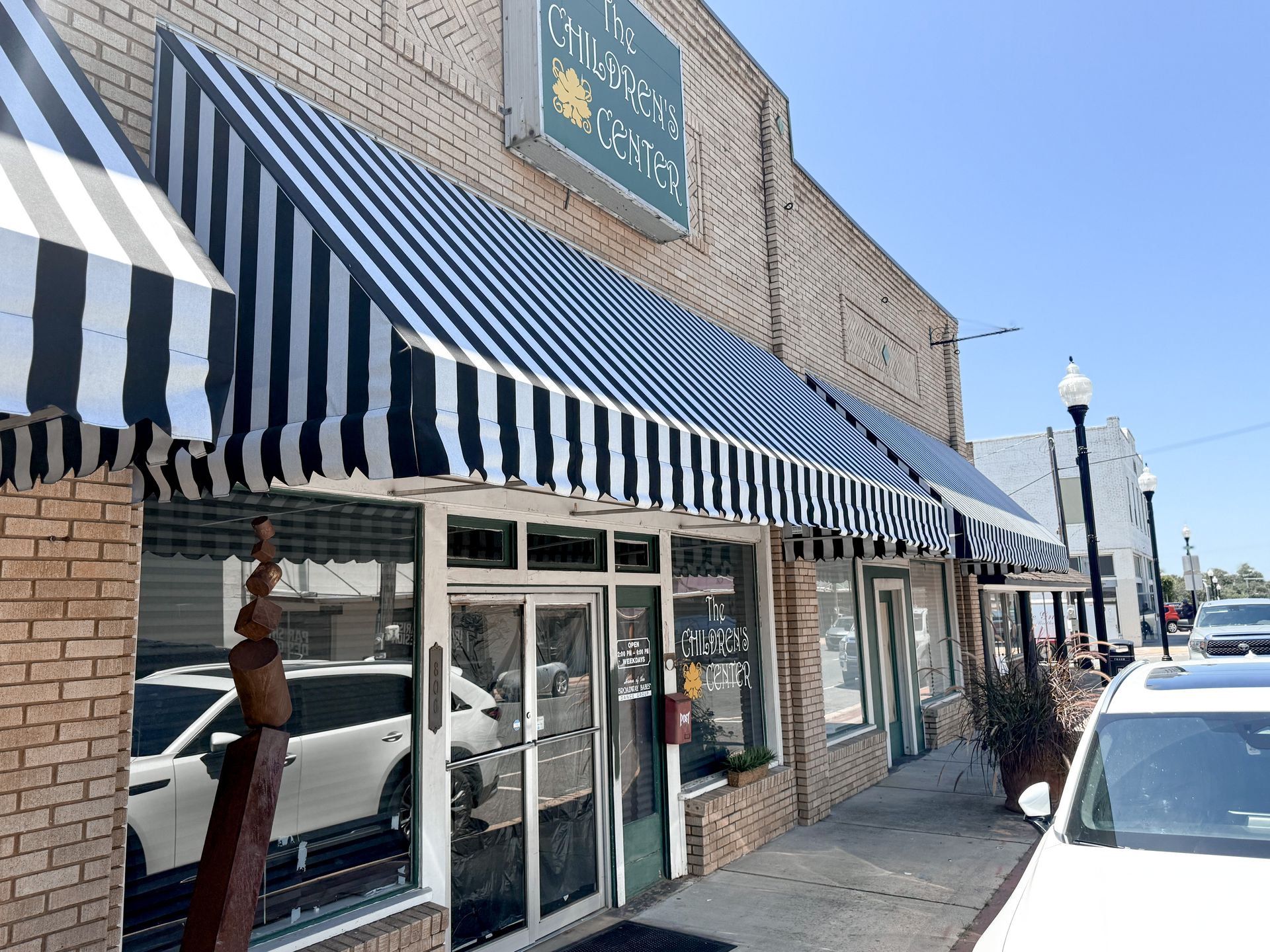 A storefront with black and white striped awnings. The sign reads 