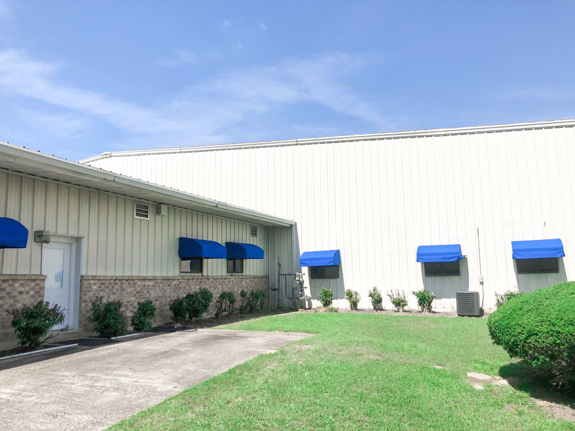 A building with blue awnings and a grass yard on a sunny day.