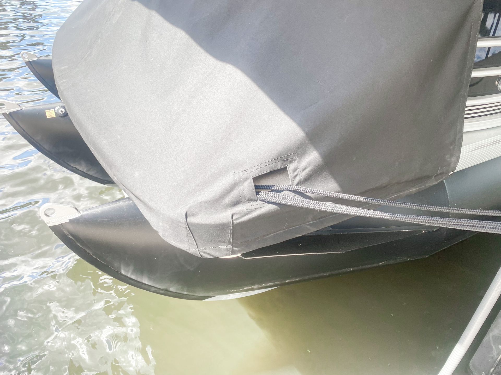 Black inflatable boat stern with a gray cover, tied with a rope.
