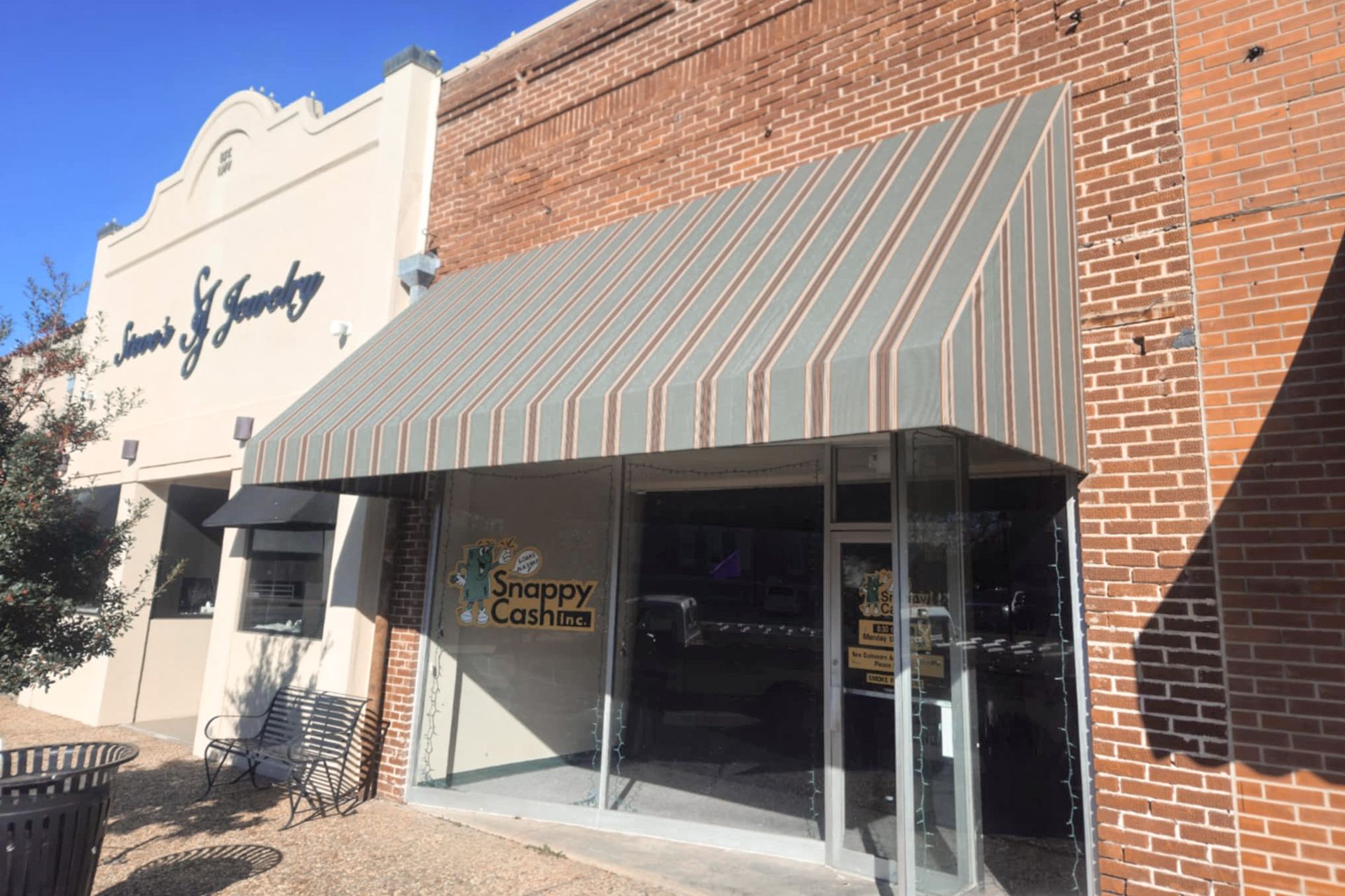 Exterior view of Scrappy Cafe, store front with striped awning, brick and beige buildings.