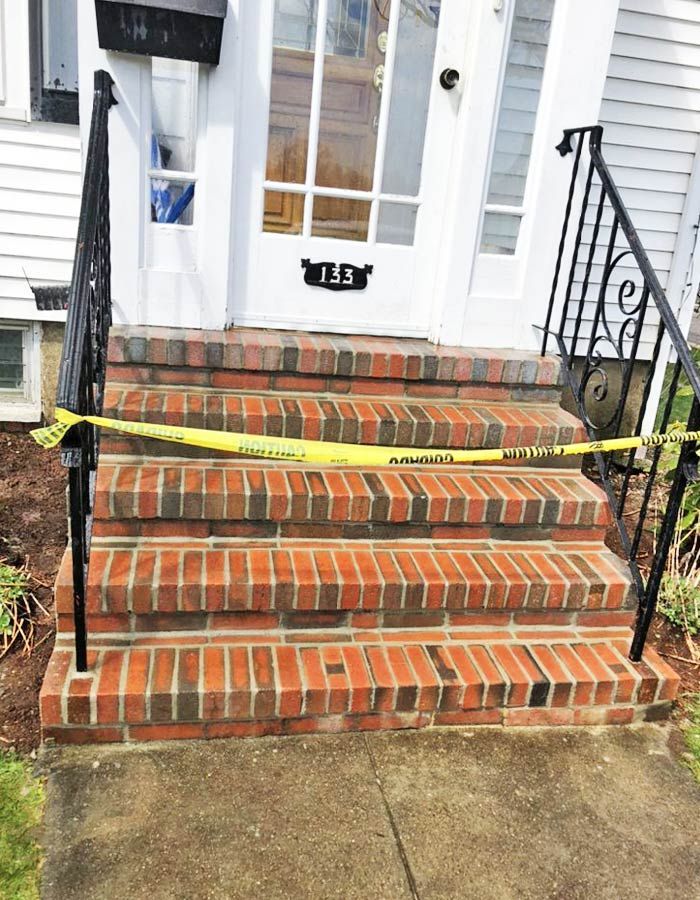 Brick front steps leading to a white house entrance with black railings and a glass-paneled door