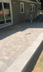 Paver patio beside a house with a person standing near the wall in the background