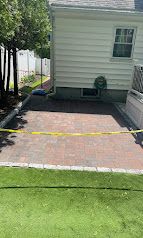 Brick patio behind a house, cordoned off with yellow tape beside a green lawn.