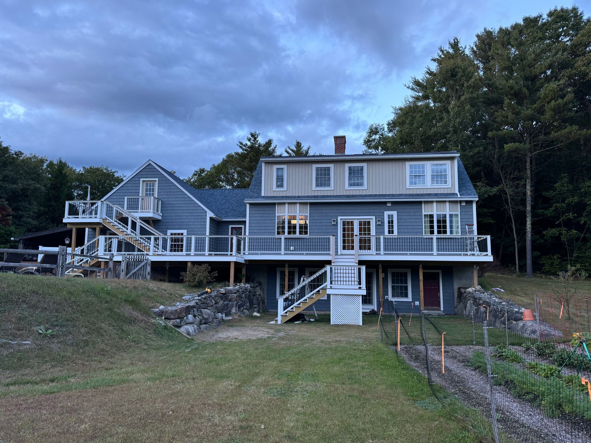 A large house with a large deck in the middle of a field.