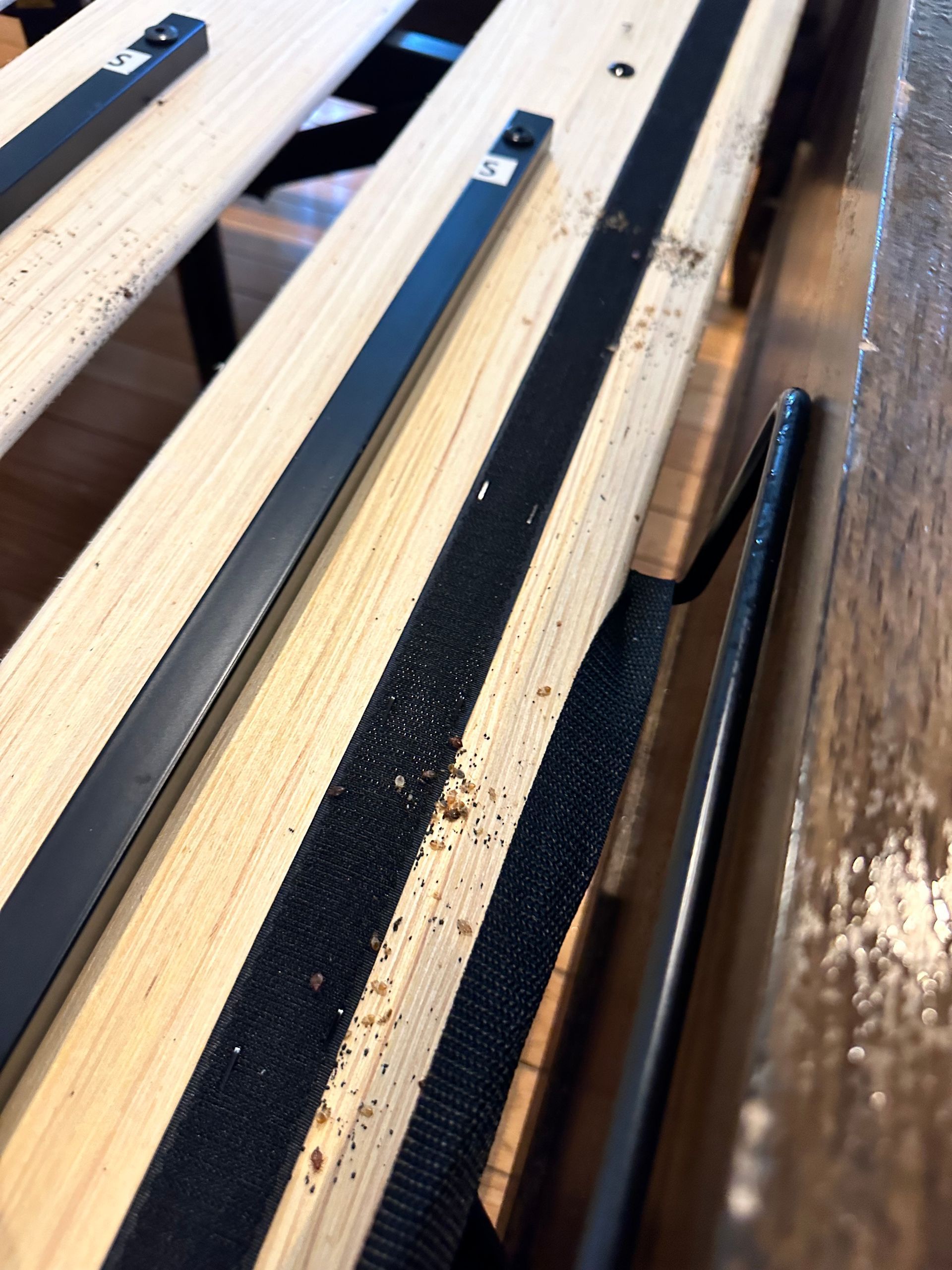 Wooden slats with black strips stacked closely on a pallet or rack in a workshop