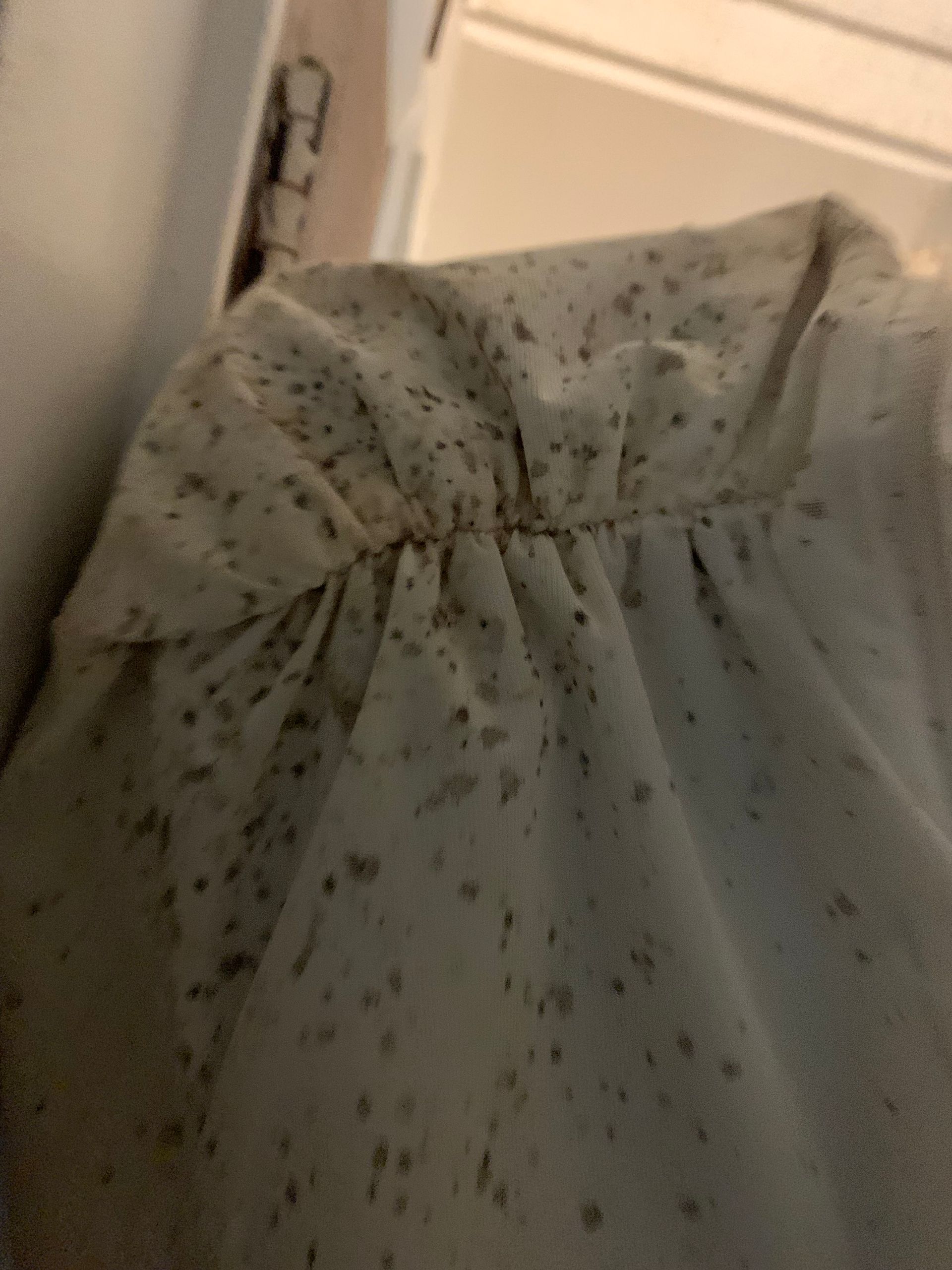Light gray fabric with dark specks and gathered stitching near a doorframe