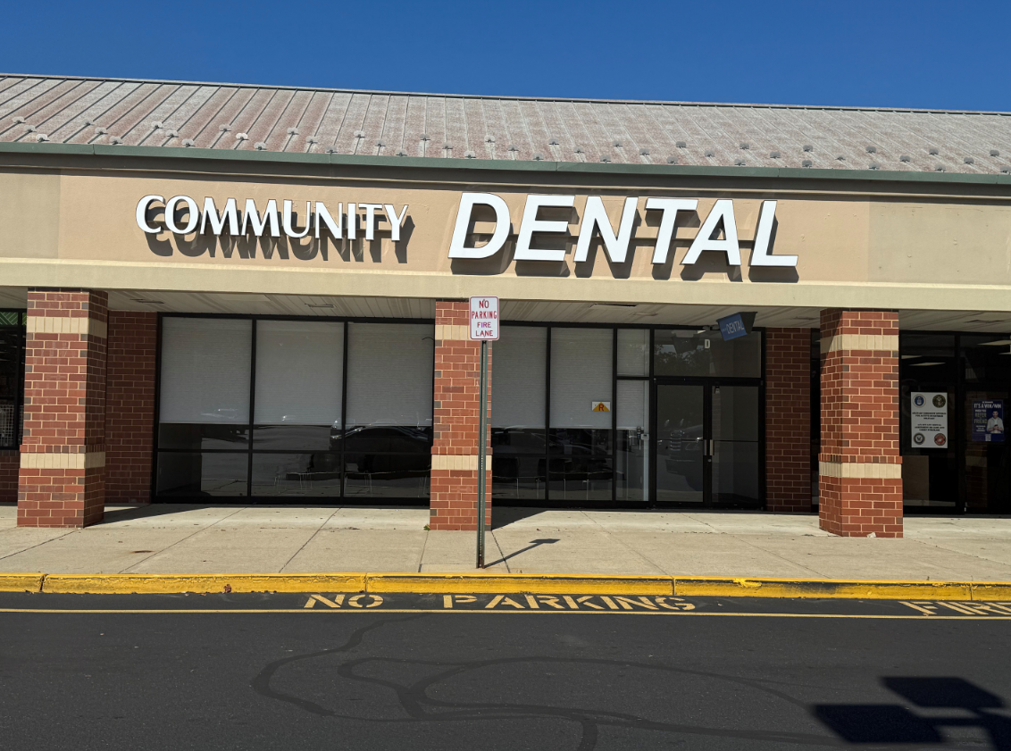 Community Dental office front, beige facade, white letters, brick pillars, parking area.