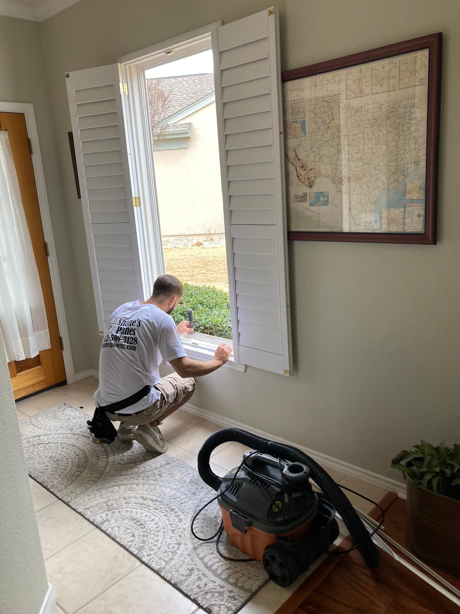A man is cleaning a window with a vacuum cleaner.