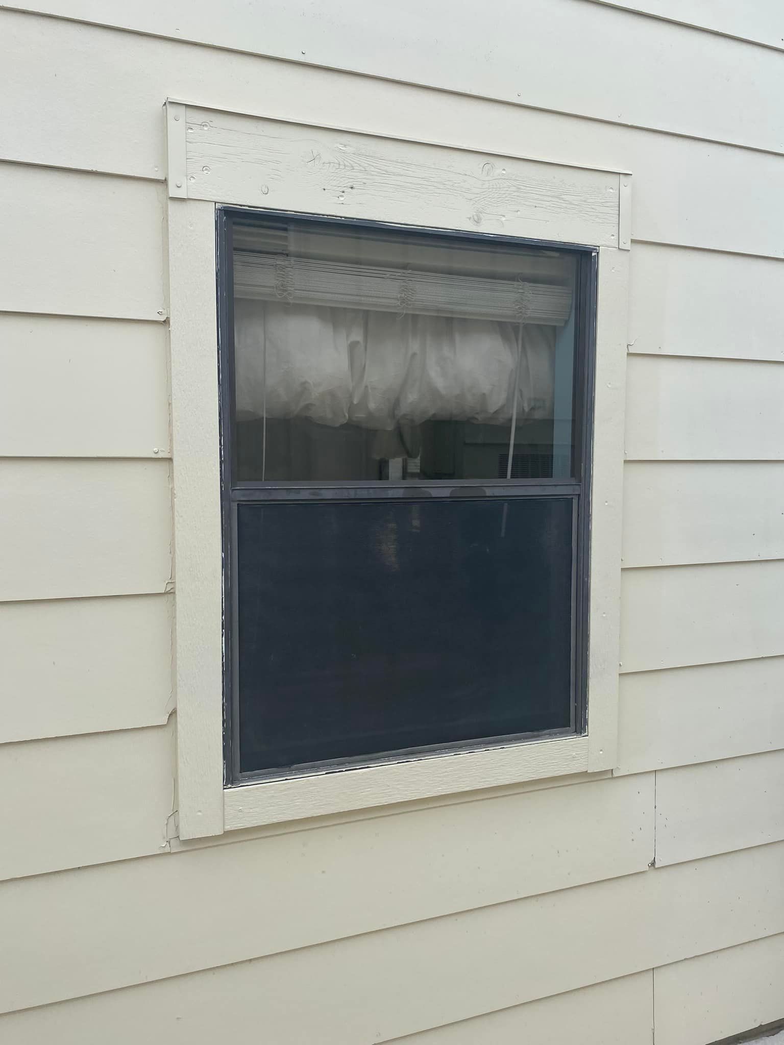 A window on the side of a house with a black frame