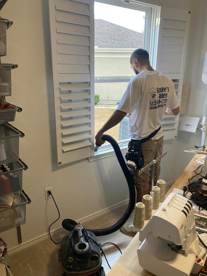 A man is cleaning a window with a vacuum cleaner.