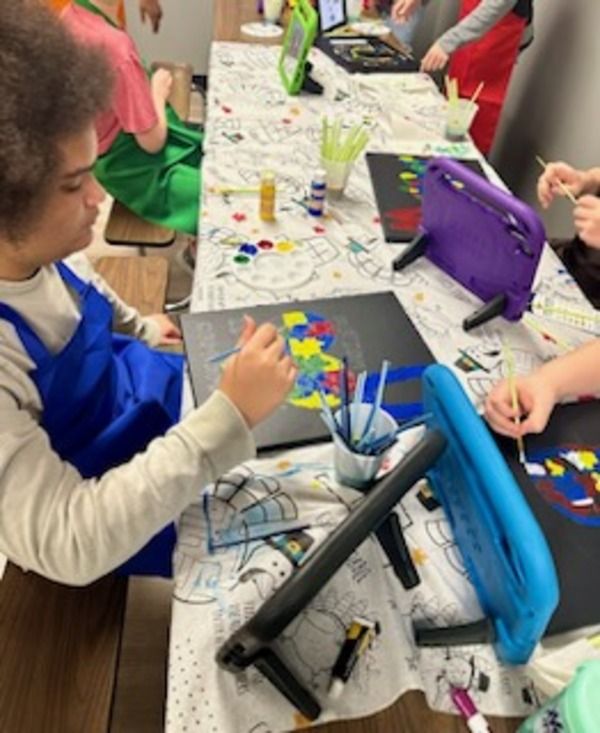 A group of children are sitting at a table painting