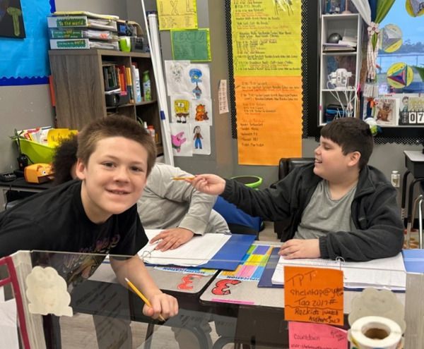 A group of young boys are sitting at desks in a classroom.