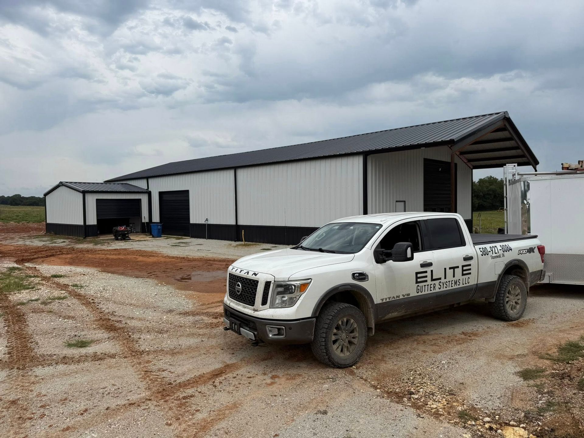 White pickup truck in front of a white and black building under a cloudy sky.