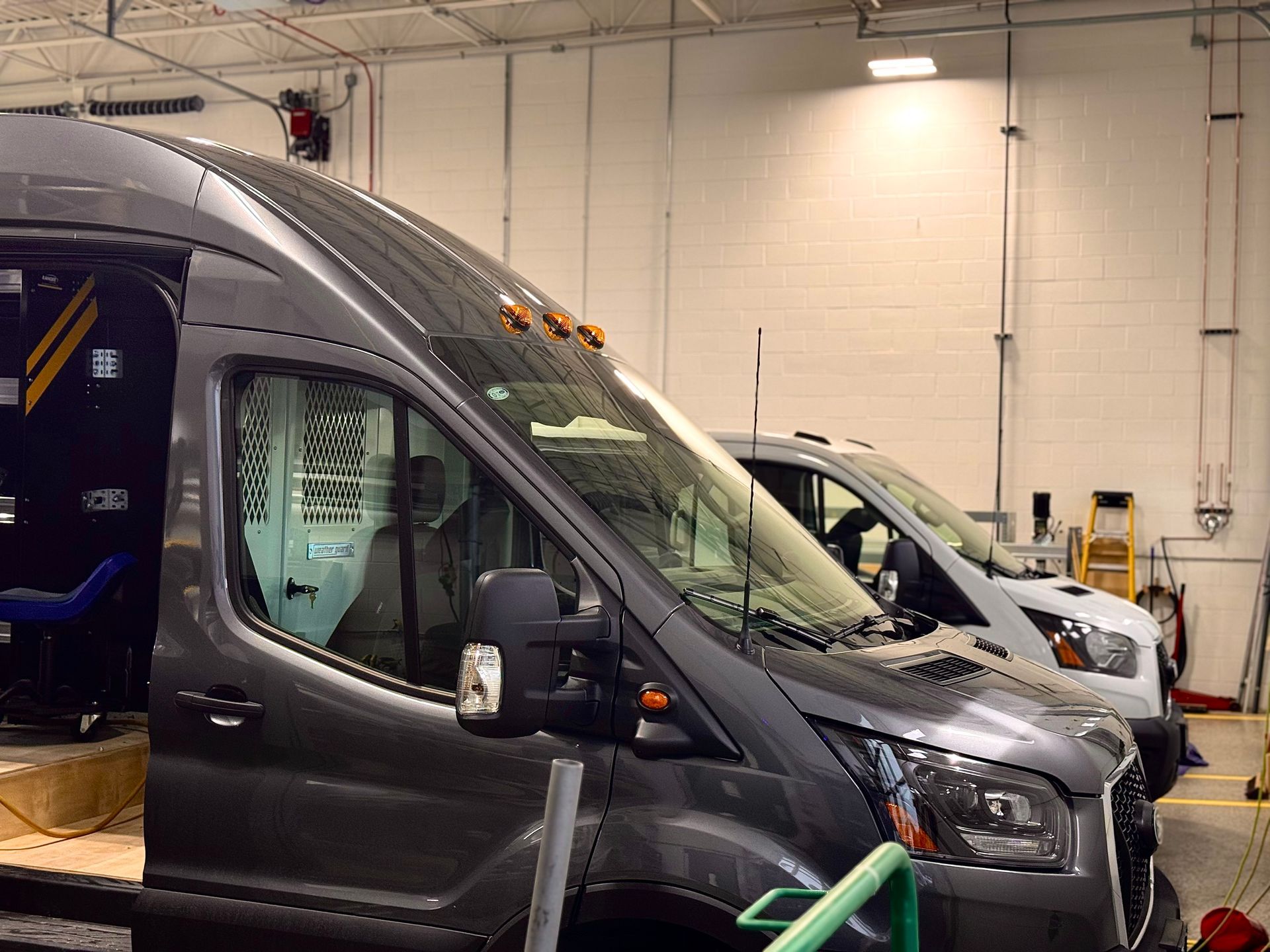 Dark gray van and white truck parked inside an auto service garage