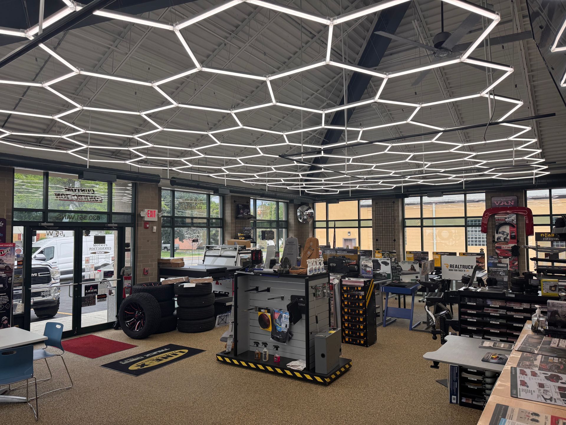 Modern gym interior with hexagonal ceiling lights, equipment, and large windows