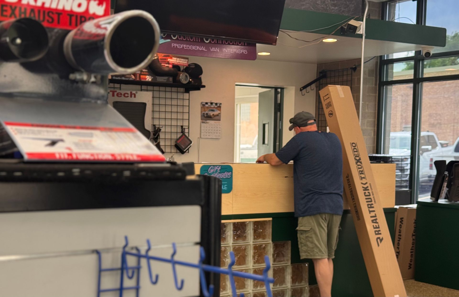 Man standing at a counter in an indoor shop, with boxes and tools nearby.